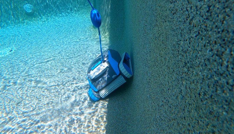 The Dolphin Escape cleaning the base of a pool wall underwater